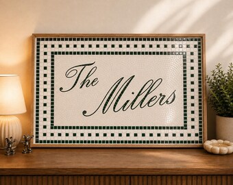 May include: A rectangular wall sign featuring a mosaic tile design with a white background and a dark green border. The text "The Millers" is written in a dark green cursive script in the center. The sign is enclosed in a light wood frame.