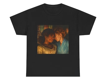 May include: Black t-shirt featuring a painting of two women with their foreheads touching. The artwork depicts the women in a close embrace, with one wearing a light-colored top and the other in a blue garment. The image has a warm, vintage aesthetic.