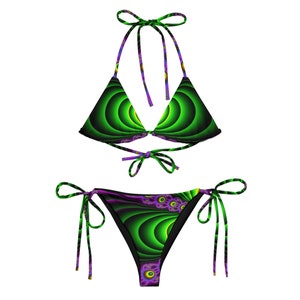 Puede incluir: Bikini verde y morado con un patrón de remolino. La parte superior es de estilo triangular con tirantes ajustables y lazos en la parte posterior. La parte inferior es de estilo atrevido con lazos en los lados.