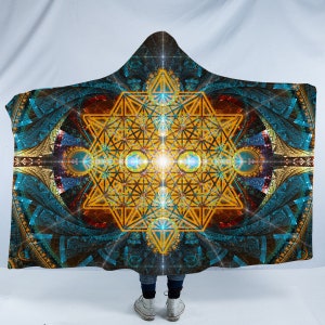 May include: Hooded blanket featuring a vibrant geometric design in shades of gold, teal, and blue. The intricate pattern includes a central starburst and symmetrical shapes, creating a visually striking and artistic piece.