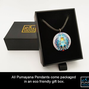 May include: A round pendant with a colorful, intricate design, displayed in an open black gift box. The pendant hangs on a black cord. The box is next to a closed black box with gold lettering. The text reads: All Pumayana Pendants come packaged in an eco friendly gift box.