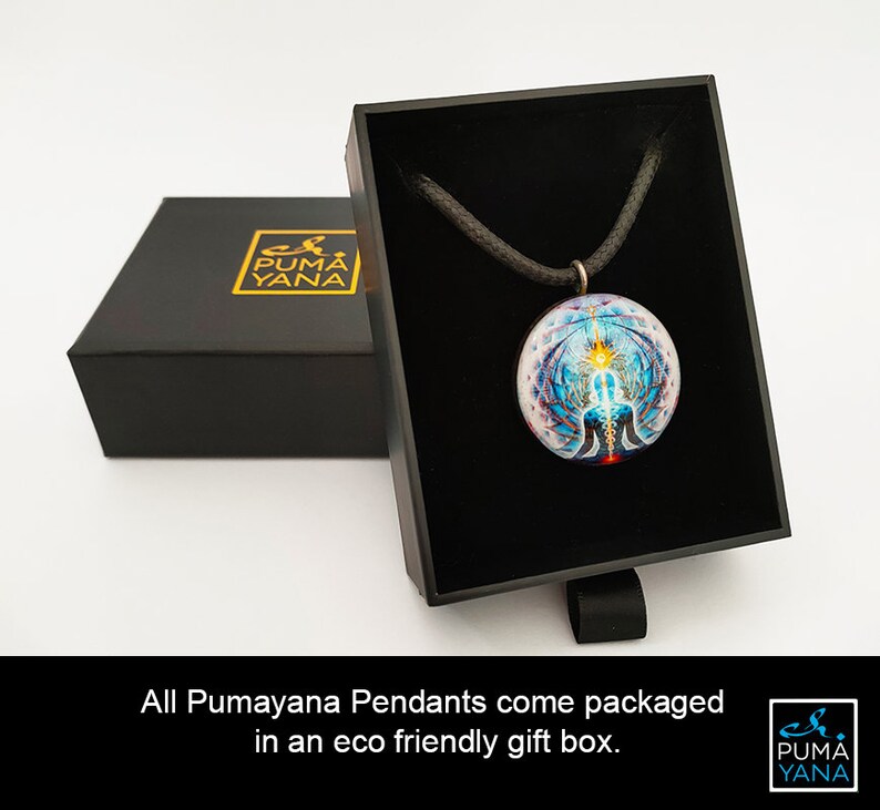 May include: A round pendant with a colorful, intricate design, displayed in an open black gift box. The pendant hangs on a black cord. The box is next to a closed black box with gold lettering. The text reads: All Pumayana Pendants come packaged in an eco friendly gift box.