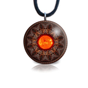 May include: A round pendant necklace featuring a detailed, brown and orange mandala design surrounding a bright orange sun. The pendant hangs from a black cord. The design is symmetrical and intricate, with a glossy finish.