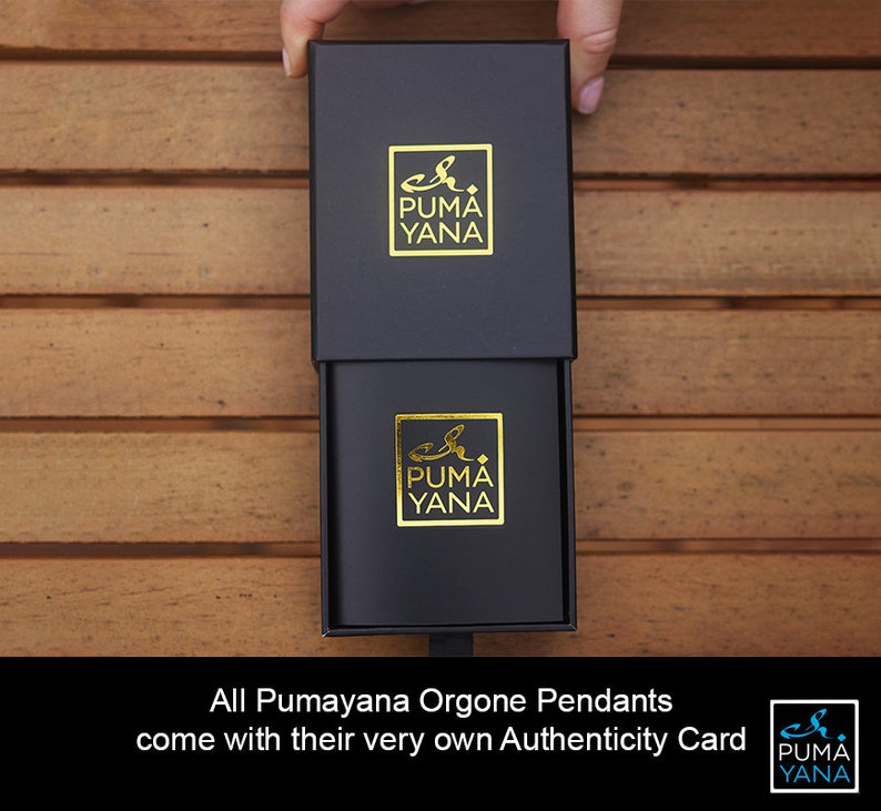 May include: Black box with a gold logo that reads "Puma Yana". The box is open, revealing a smaller box with the same logo. The text at the bottom reads "All Pumayana Orgone Pendants come with their very own Authenticity Card."