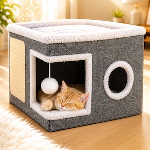 May include: A square, dark gray cat cube house with a white sherpa-lined top and interior. It features a side scratching pad, a circular cutout entrance, a large open front entrance with a hanging white pom-pom toy, and a sleeping ginger cat.