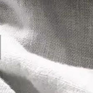 Op de afbeelding: Een textielstof met een herhalend patroon van brede horizontale strepen in afwisselende tinten wit en lichtgrijs. Het materiaal vertoont een zichtbare geweven textuur met een consistent rasterachtig weefpatroon over het gehele oppervlak.