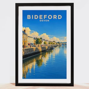 May include: A framed travel poster featuring a vibrant blue sky over the Bideford, Devon waterfront. The scene depicts stone buildings along a quay with reflections in the water, under the text BIDEFORD DEVON in a clean, sans-serif font.