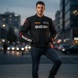 Peut inclure: Veste de moto noire avec le logo Suzuki blanc sur la poitrine et les manches. Des touches de rouge sont visibles sur les épaules et les manches, et le logo Michelin est également présent. La personne porte un jean bleu et des bottes noires.