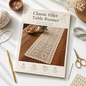 May include: A printed instructional booklet titled Classic Fillet Table Runner featuring a beige crocheted runner on a wooden table, surrounded by a gold crochet hook, scissors, a needle, a ball of yarn, and stitch markers on a white surface.