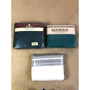 Puede incluir: Tres sábanas planas de franela empaquetadas. Una sábana individual verde oscuro High Sierra etiquetada como 178 x 254 cm, una sábana matrimonial verde oscuro Sierra Home Collections y una sábana individual blanca Celebration. Todas de franela 100% algodón.