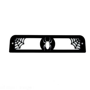 May include: Black rectangular decorative piece with a spider and web design. The center features a spider silhouette within a circle, flanked by spiderwebs on each end. The design is cut out, creating negative space.
