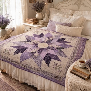 Peut inclure: Une couverture matelassée avec un motif d'étoile dans des tons de violet et de crème. La couverture est posée sur un lit avec du linge blanc et une jupe de lit bordée de dentelle. La chambre est décorée dans un style vintage avec des accents de lavande.