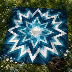 May include: A square quilt featuring a large, multi-pointed star pattern in a gradient of blue, teal, and white shades. The design consists of concentric, angular geometric layers radiating from a central white point, with visible linear stitching.