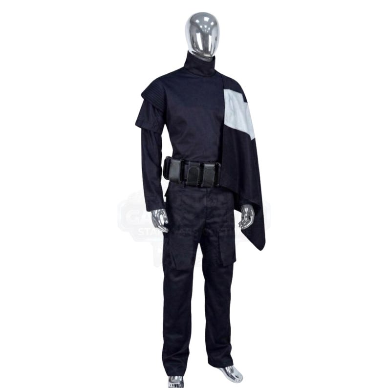 May include: A dark navy blue costume set featuring a high-neck long-sleeve top with a white shoulder panel, a matching dark navy blue utility belt with multiple rectangular pouches, and dark navy blue cargo-style trousers on a silver mannequin.