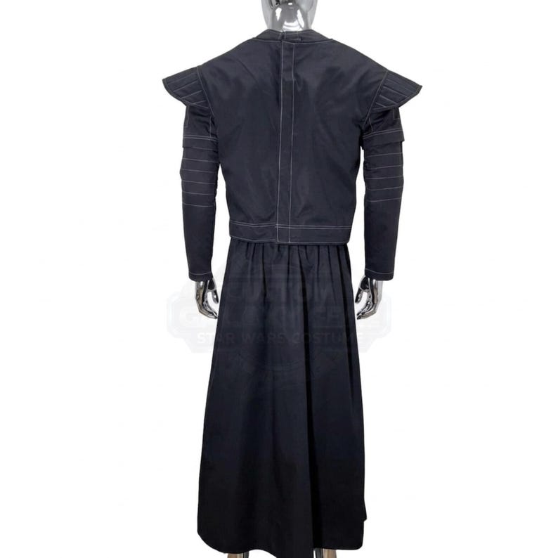 K&ouml;nnte beinhalten: Ein schwarzes Ensemble aus einer lang&auml;rmeligen Jacke und einem bodenlangen Rock auf einer Schaufensterpuppe. Die Jacke hat strukturierte Schulterpolster, horizontale Steppn&auml;hte an den &Auml;rmeln und eine vertikale Naht in der Mitte des R&uuml;ckens.