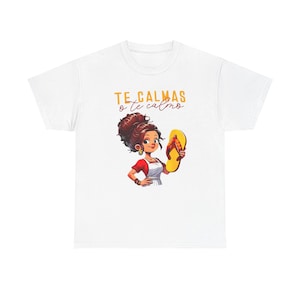 以下が含まれることがあります： 白いTシャツに、高い位置でお団子ヘアにまとめ、赤いシャツと白いエプロンを着用し、黄色いビーチサンダルを持っている人物のグラフィックイラストが描かれています。人物の上には、黄色と赤で「TE CALMAS o te calmo」というテキストが記されています。