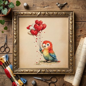 May include: A framed cross-stitch picture of a parrot with heart-shaped balloons. The parrot is multi-coloured, with red, orange, yellow, and blue feathers. The gold frame has heart and bird motifs. The background is a light beige fabric.