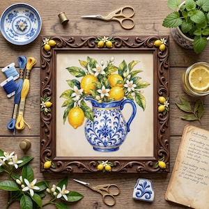 May include: A framed embroidery art piece featuring a blue and white pitcher filled with lemons and white blossoms. The dark wood frame is decorated with sculpted lemon motifs. Surrounding items include embroidery floss, scissors, and a notebook.