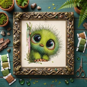 May include: A cross-stitch embroidery of a fuzzy green creature with large dark eyes, framed in a decorative bronze-colored frame featuring sculpted frogs, dragonflies, and stones. The artwork is surrounded by embroidery floss and scissors.