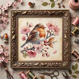 May include: A framed cross-stitch of a robin perched on a flowering branch, surrounded by pink blossoms. The ornate, gold-toned frame is decorated with bird and floral motifs. Spools of thread, scissors, and small bird figurines complete the craft-themed scene.