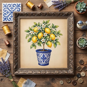 May include: A framed cross-stitch embroidery featuring a lemon tree with yellow fruit, green leaves, and white blossoms planted in a blue and white patterned ceramic pot. The artwork is set within an ornate, dark metallic-toned picture frame.