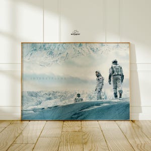 Peut inclure: Une affiche encadrée représentant une scène du film Interstellar. L'image montre trois astronautes en combinaisons spatiales blanches sur un paysage glacé aux tons bleus, avec une chaîne de montagnes en arrière-plan. Le mot "INTERSTELLAR" est imprimé à gauche.