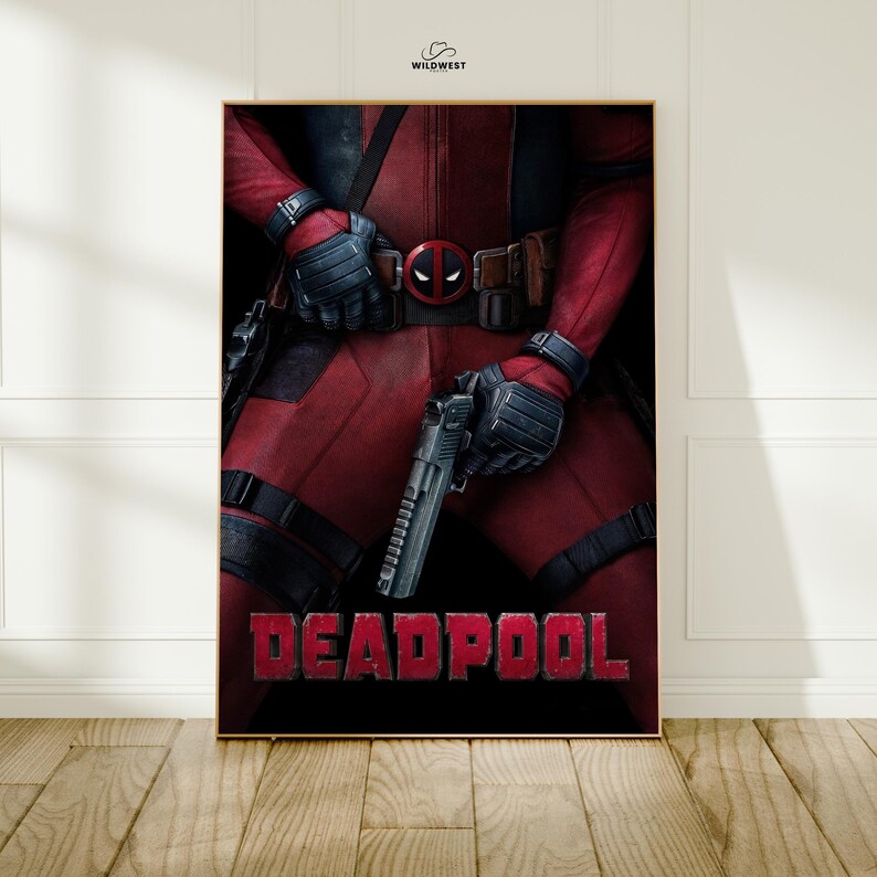 May include: A framed poster featuring the character Deadpool. The image shows Deadpool in a red and black costume, holding a gun. The word "DEADPOOL" is displayed in red block letters at the bottom of the poster. The Wildwest logo is in the top right corner.