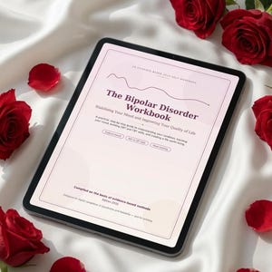 Puede incluir: Una tableta que muestra un libro de trabajo digital titulado The Bipolar Disorder Workbook: Stabilising Your Mood and Improving Your Quality of Life. La portada tiene un fondo rosa claro con texto oscuro y métodos basados en evidencia.