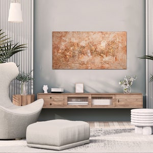 May include: A modern living room with a neutral color palette. Features a large abstract painting, a wooden media console, a comfortable armchair, and two small side tables. Potted plants and pendant lights add a touch of nature and elegance.