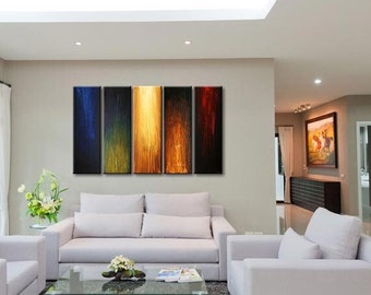 May include: A modern living room with white furniture, a gray rug, and a glass coffee table. The focal point is a five-panel abstract painting with vertical streaks of blue, black, yellow, orange, and red. The room has large windows and a bright, airy feel.