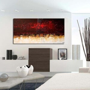 May include: Abstract painting with red, brown, and gold hues. The painting is displayed on a white wall in a modern living room setting with a white couch and a vase of brown branches.