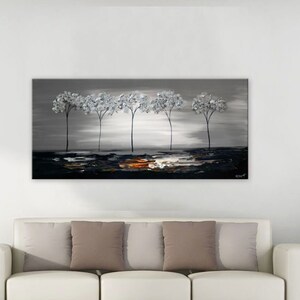 May include: A painting of a row of five silver trees against a gray background with a hint of orange in the foreground. The painting is hanging on a white wall in a living room setting.