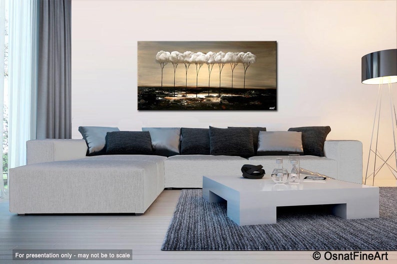 May include: Abstract painting of a row of white trees with brown trunks against a brown background. The painting is displayed on a wall in a living room setting with a white couch, a coffee table, and a floor lamp.