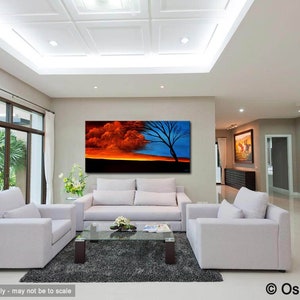 May include: A large abstract painting of a sunset with a tree in the foreground. The sky is a mix of orange, red, and blue. The tree is silhouetted against the sky. The painting is hanging on a wall in a living room.