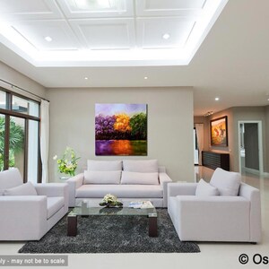May include: A living room interior with a large abstract painting of trees in shades of purple, yellow, and green hanging on the wall. The painting is above a white sofa with two matching armchairs. A glass coffee table sits in front of the sofa.