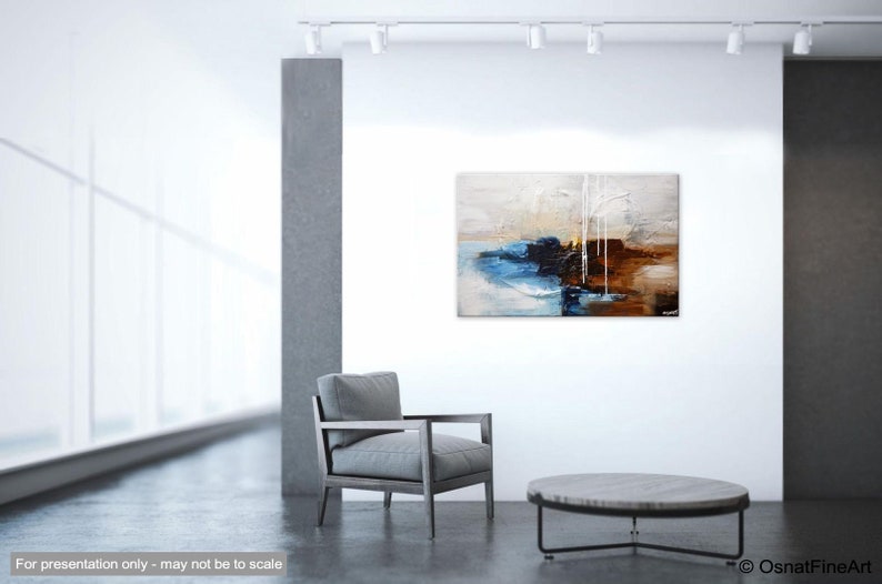 May include: Abstract painting with blue, brown, and white paint on a canvas. The painting is hanging on a white wall in a modern living room setting.