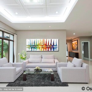 May include: Abstract painting of colorful sailboats on a white background with a reflection in the water. The painting is displayed in a living room with white furniture and a gray rug.