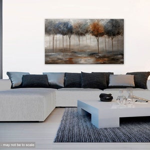 May include: Abstract painting of a forest scene with trees in shades of blue, brown, and gray. The trees are silhouetted against a misty background. The painting is displayed on a wall in a living room setting.