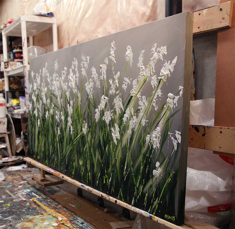 May include: A large abstract painting of white flowers on a gray background. The flowers are painted with thick, textured strokes of paint, giving them a three-dimensional appearance. The painting is on a canvas and is stretched over a wooden frame.