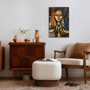 May include: A painting of a stylized human face with a golden background and blue accents. The painting is framed and hanging on a white wall in a living room setting.