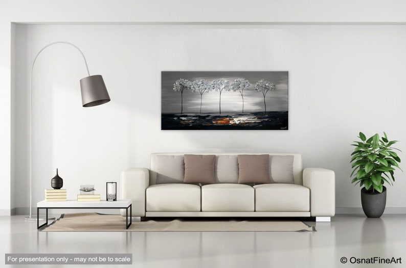 May include: A painting of a row of five silver trees against a gray background with a hint of orange in the foreground. The painting is hanging on a white wall in a living room setting.