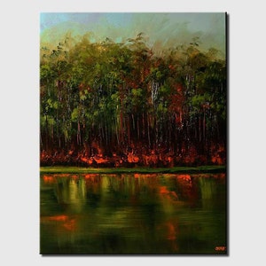 May include: A painting of a forest reflected in a still lake. The trees are a deep green with hints of red and orange, creating a warm and inviting scene.