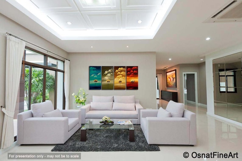 May include: A living room interior design with a white sofa, two white armchairs, and a glass coffee table. A four-panel abstract painting of trees in different seasons hangs on the wall.