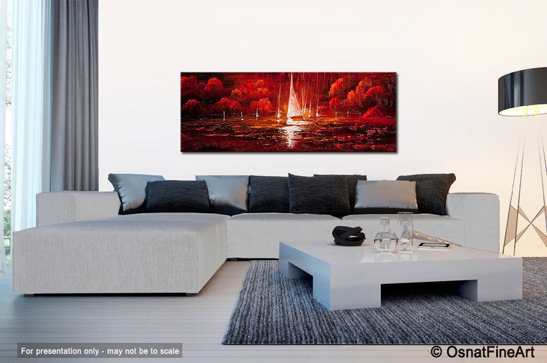May include: A panoramic oil painting depicting sailboats on a body of water at sunset. The artwork features a vibrant color palette of red, orange, and white, with the sailboats' sails illuminated by the setting sun. The painting is displayed above a modern white sofa.