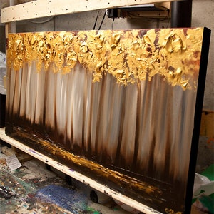 May include: Abstract painting of a forest scene with gold leaf accents. The painting is on a canvas with a black frame.