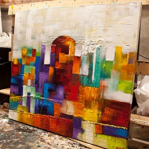 May include: Abstract painting with a textured surface. The painting features a variety of colors, including red, orange, yellow, green, blue, purple, and white. The colors are arranged in a geometric pattern, creating a sense of movement and energy.