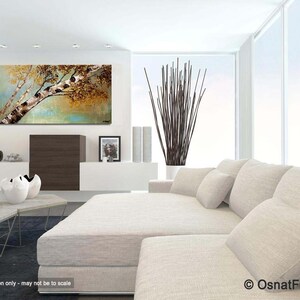 May include: A painting of a birch tree with a white trunk and brown branches against a background of green and brown leaves. The painting is hanging on a white wall in a living room setting with a white couch and pillows.