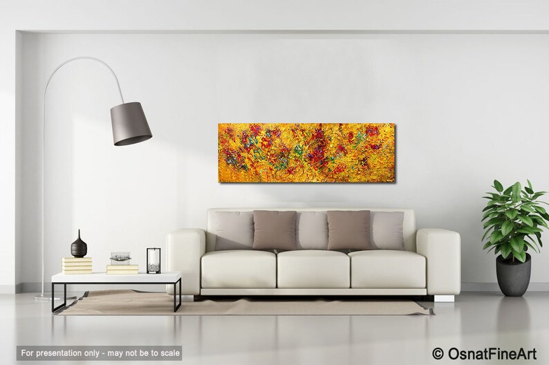 May include: Abstract painting with a yellow background and red, green, and blue accents. The painting is displayed on a white wall above a white sofa with beige pillows.