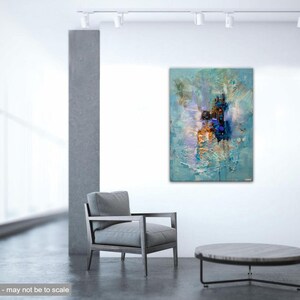 May include: Abstract painting with blue, white, and gold hues. The painting is displayed on a white wall in a modern interior setting with a gray armchair and a round coffee table.