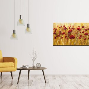 May include: A painting of a field of red poppies against a golden background. The painting is displayed on a white wall in a living room setting with a yellow armchair and a coffee table.